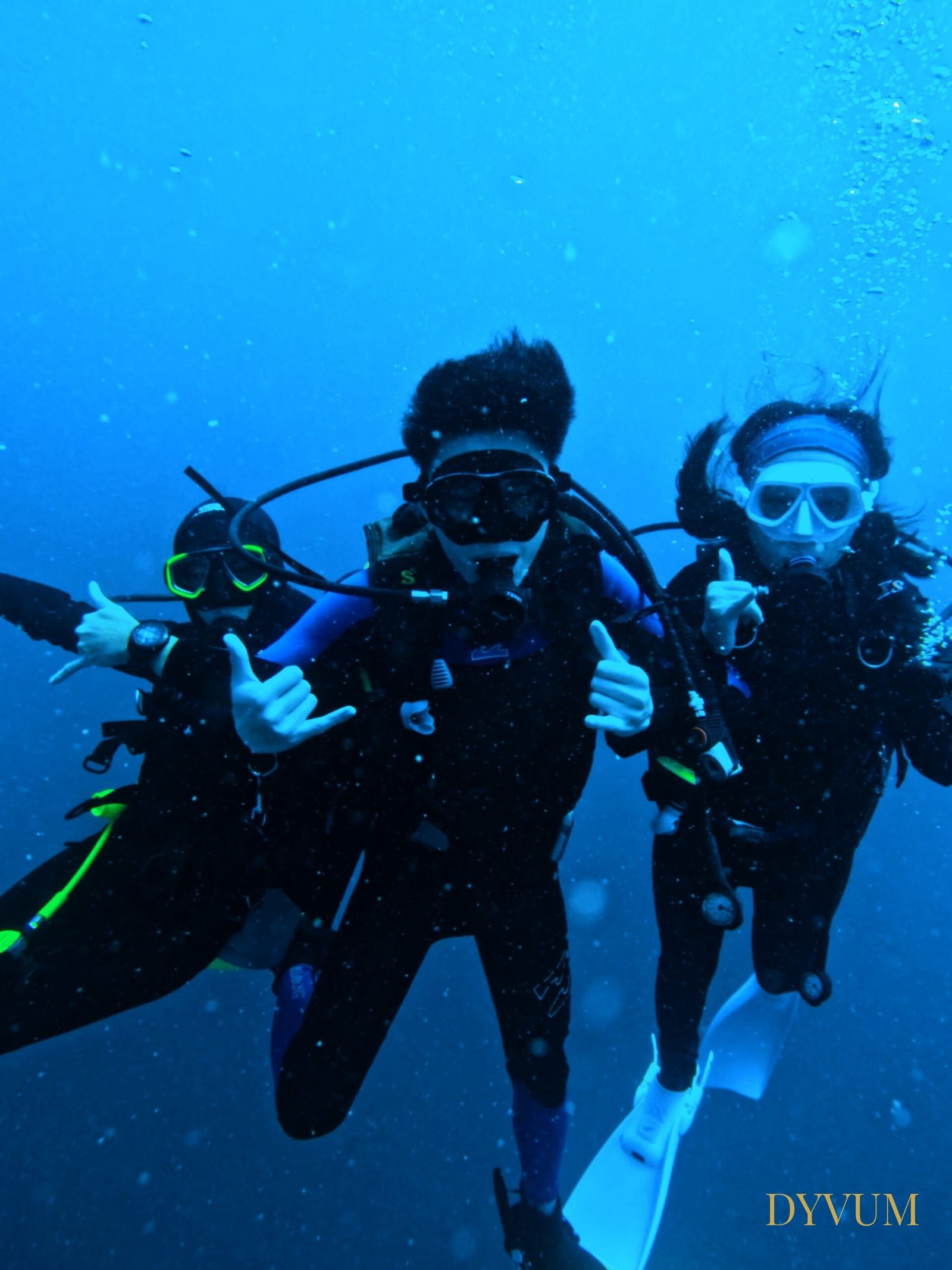 Three DYVUM divers giving hand signals underwater during an Open Water & Advanced Open Water bundle trip