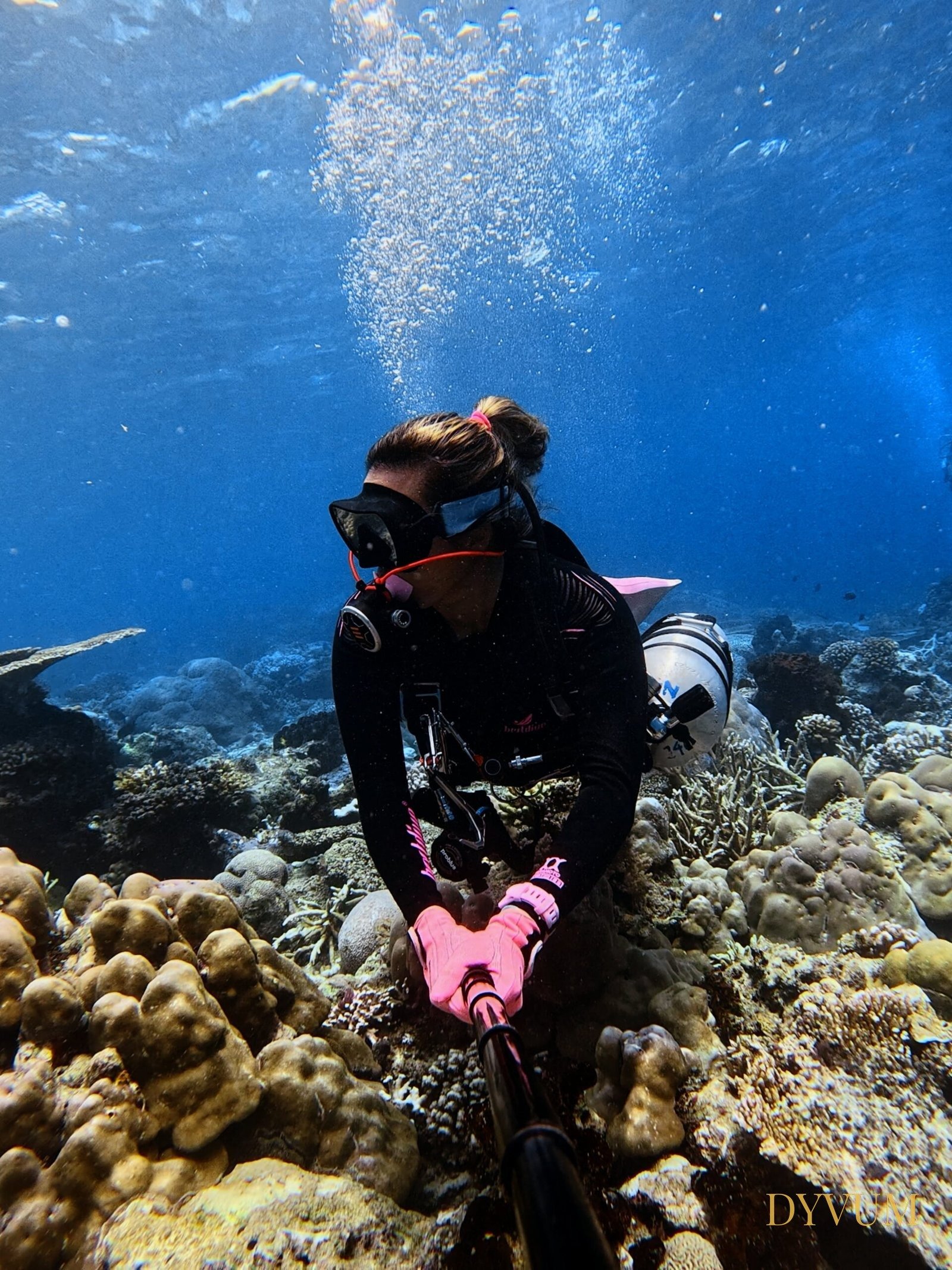 DYVUM founder Pagan diving in sidemount configuration along a coral reef