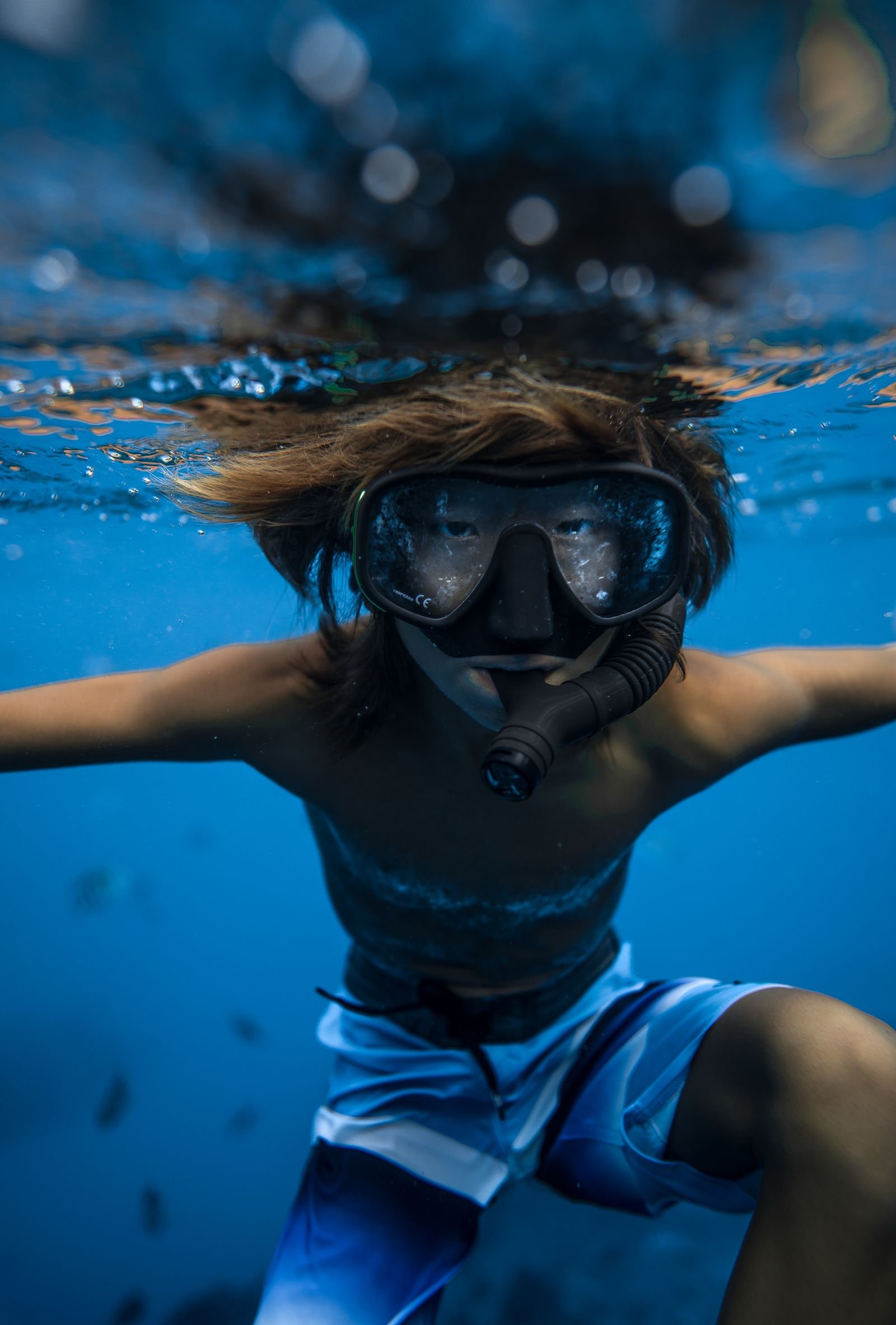 Young PADI Seal Team diver in mask and snorkel with arms outstretched underwater